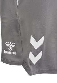 Grå sportsshorts med hvid hummelbi-logo og to hvide nedadgående chevron-striber på sidesømmen.