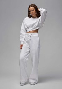 Sudadera recortada gris y pantalones de chándal de pierna ancha hechos de un tejido suave. Presenta una cintura con cordón y una etiqueta de logo en los pantalones.