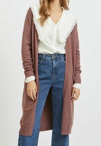 Lång cardigan med öppen front i dammig rosafärgad stickad material med ribbade ärmslut, tillsammans med en vit blus som har en stor spetskrage och högmidjade jeans.