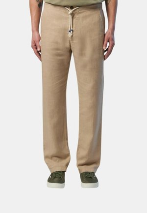 Pantaloni in lino beige con vita elasticizzata, caratterizzati da una chiusura con bottone e tasche laterali, abbinati a sneakers verdi.