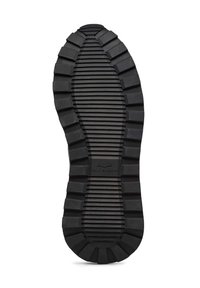 Suola di scarpa in gomma nera con superficie texture, caratterizzata da scanalature orizzontali e verticali, con un logo centrato vicino al fondo.