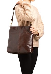 Bruine lederen schoudertas met een gladde afwerking, voorzien van een diagonale naad, een afneembare schouderband en afgeronde hoeken.