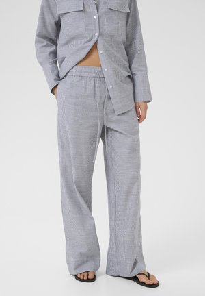 Camicia leggera grigia a righe con bottoni sul davanti e due tasche sul petto, abbinata a pantaloni larghi con cordoncino coordinati.