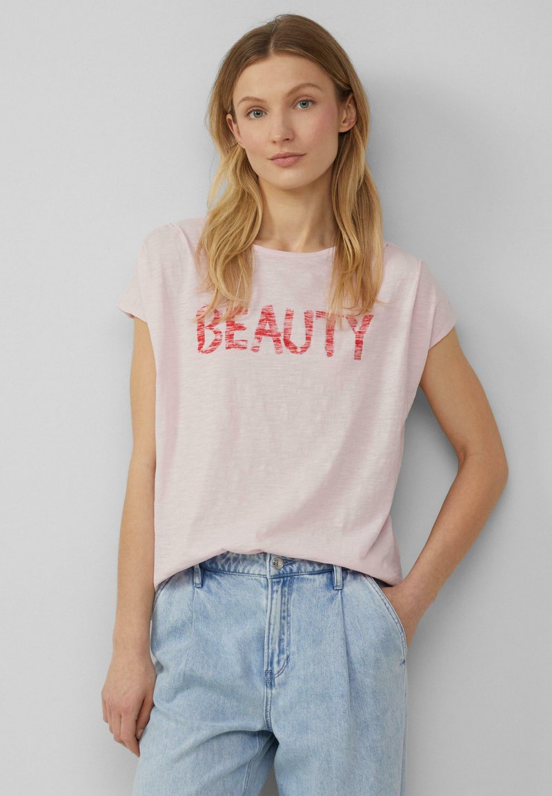 Lichtroze t-shirt met korte mouwen met het woord "SCHOONHEID" in vet, rode letters. Casual pasvorm met een zachte, gemarmerde stof.