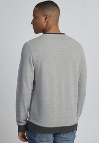 Grauer Sweatshirt mit strukturiertem Finish, schwarzem geripptem Rundhalsausschnitt und -bündchen sowie einem dunklen grauen Bund; von hinten betrachtet.