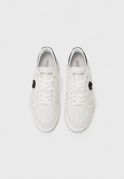Valge Roberto Cavalli sneakerite paar, millel on perforatsiooniga varvas, paelad ja must logodetail külgedel, vaadatuna ülalt.