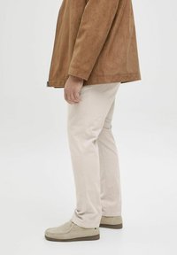 Veste en daim beige clair, pantalon beige et chaussures en daim grises. Design simple avec une coupe décontractée. La texture est lisse et douce.
