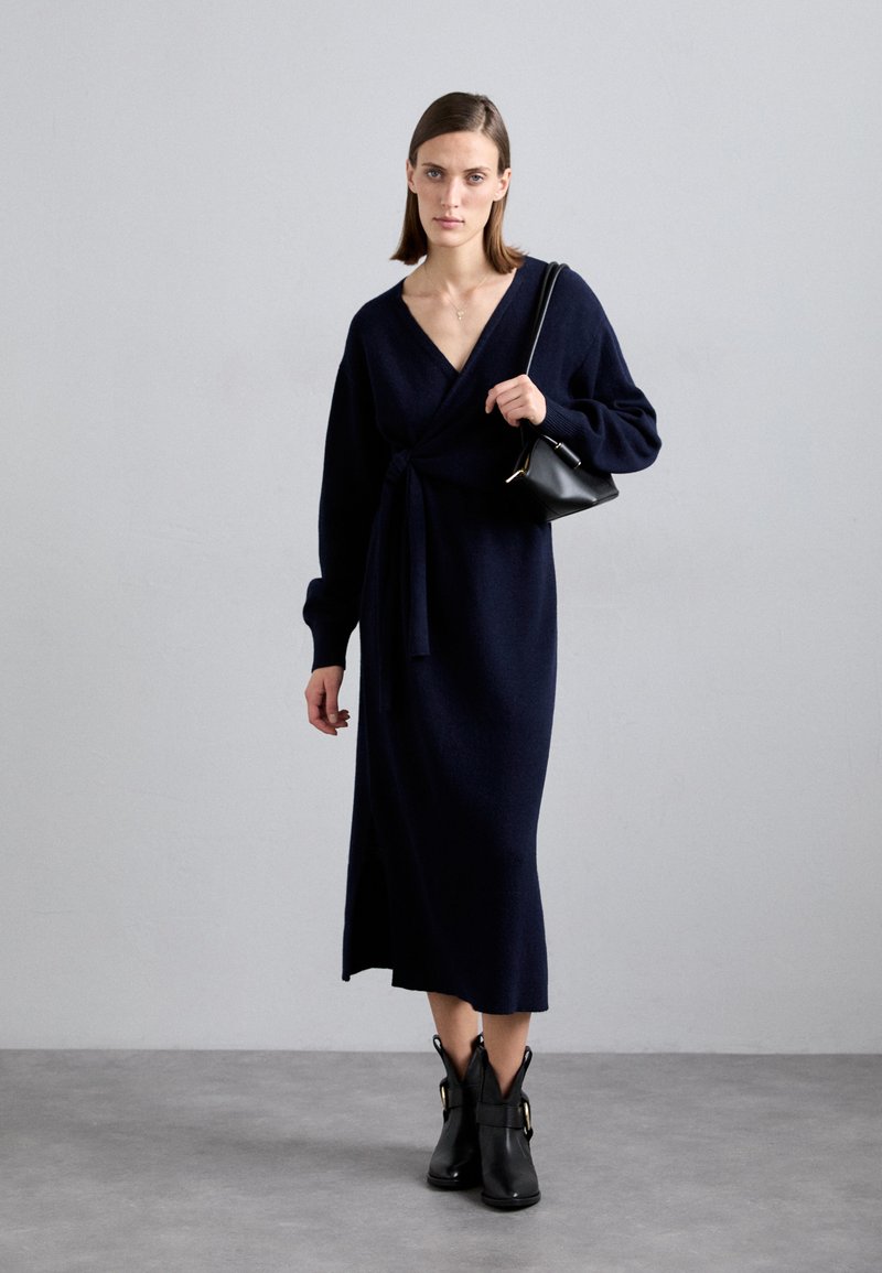 Laivank blue knitted wrap dress with long sleeves, a tie at the waist, and a side slit, paired with black ankle boots featuring gold accents.