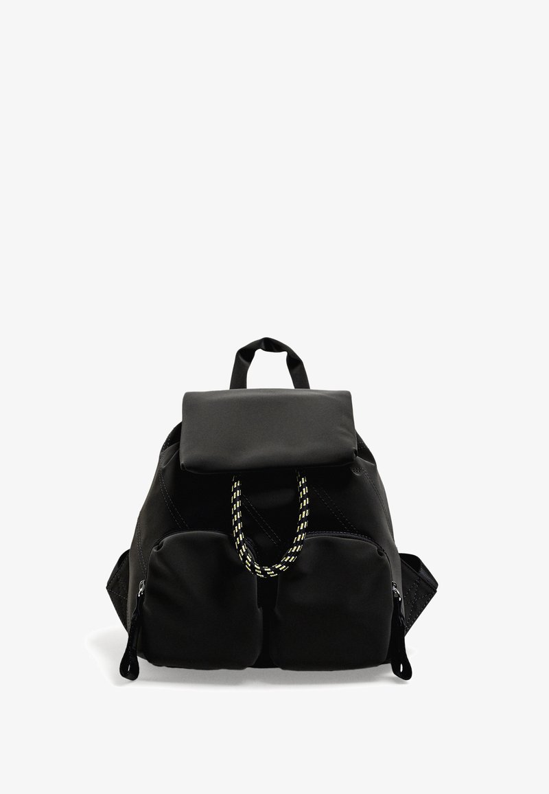 Zaino in tessuto nero con patta, manico decorativo in corda gialla, due tasche frontali con zip e spallacci imbottiti. Design elegante e funzionale.