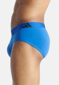 Blå bomullsboxer med svart midjeband som har tre vertikala ränder, åtsittande design, slät textur och elastiskt material för komfort.