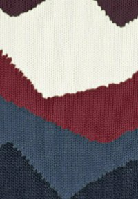 Pattern a maglia ondulata che mostra strati di crema, marrone scuro, rosso scuro, blu e blu navy, creando un effetto visivo texture.