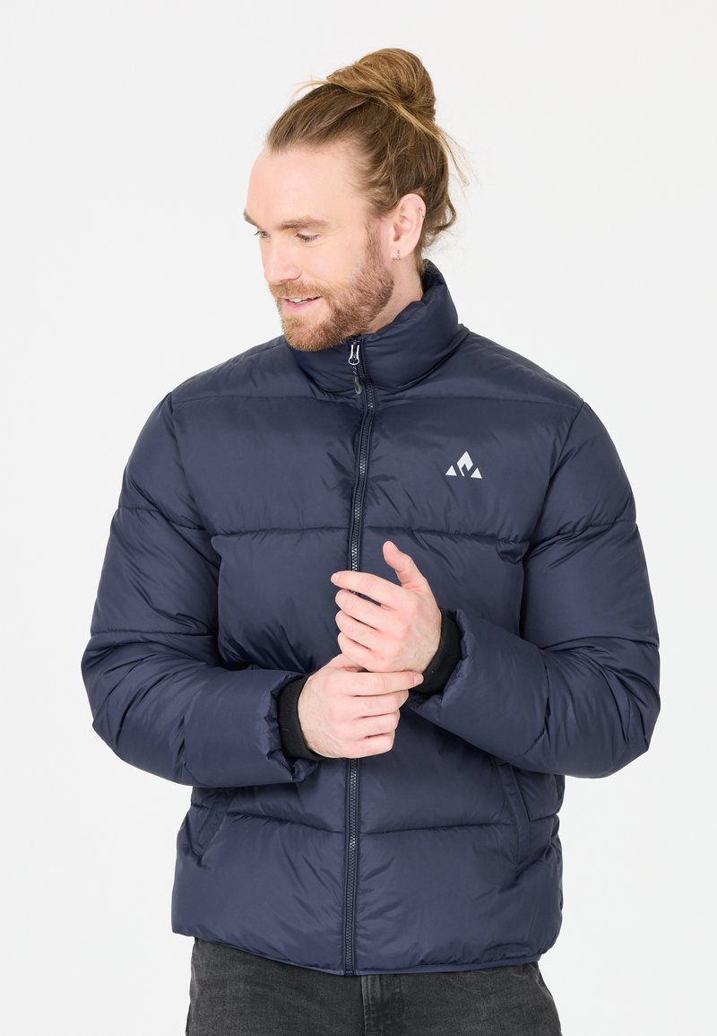 Veste matelassée bleu marine avec un col élevé, fermeture éclair à l'avant et poignets élastiques. Dotée d'un design matelassé horizontal et d'un petit logo sur la poitrine.
