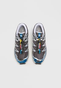 Par paščastih sivi in modrih tekaških čevljev Salomon z sistemom hitrega vezanja, belim notranjim oblogo in večbarvnimi logotipi, pogledano od zgoraj.