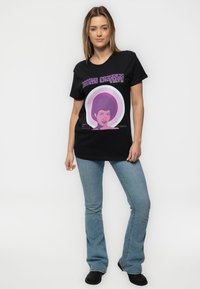 Black t-shirt featuring a colorful graphic of a female figure with a retro hairstyle, styled with a circular purple background.