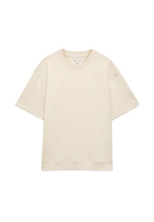 Beżowy t-shirt z krótkim rękawem i okrągłym dekoltem, luźny krój i obniżone szwy na ramionach, pokazany na białym tle.