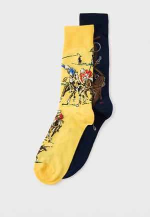 Pár posádkových ponožiek, jedna žltá a jedna námornícka modrá, s detailnými ilustráciami hráčov póla na koňoch v akcii.
