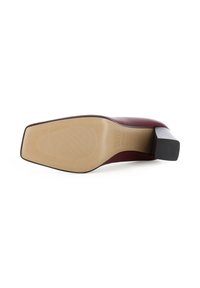 L'escarpin bordeaux à talon haut avec un bout carré et une semelle beige texturée. Le talon est épais et noir, présentant des détails de design subtils.