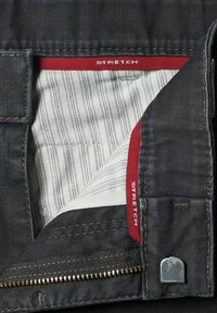 Jean en denim foncé avec une étiquette rouge "STRETCH", présentant une doublure intérieure rayée et une fermeture éclair métallique avec un tirant élégant.