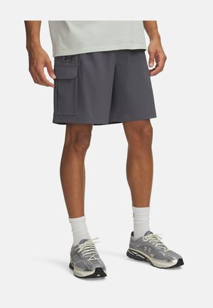 Pantalones cortos deportivos grises con un bolsillo de carga lateral, hechos de un material ligero. Se llevan con zapatillas de correr grises y calcetines blancos.
