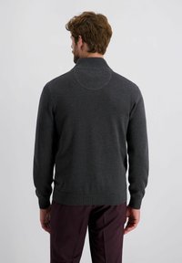 Grijze trui met een hoge kraag, ribbelmanchetten en een ribbelsoort band. Zachte textuur, aansluitend ontwerp en cirkelvormige gestikte details op de achterkant.