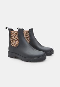 Botas de tobillo negras con un exterior de goma texturizada y paneles laterales elásticos de estampado de leopardo. Suelas gruesas para mayor agarre y lengüetas de tirón para facilitar su puesta.