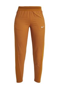 Nike Sporthosen in einem verbrannten Orangeton, aus einem atmungsaktiven Material mit Mesh-Details und einem taillierten BeinDesign. Weißes Logo auf der Vorderseite.