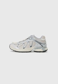 Lightweight running shoes in gray and cream, featuring a mesh upper, curved lines, and a cushioned sole with textured black rubber outsole.