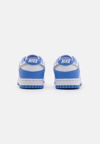 Nike tornacipők kék és fehér szintetikus bőrből, párnázott gallérral és texturált talpakkal. A saroknál megtalálható a Nike logó.