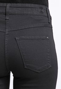 Sorte denimjeans med slim fit, subtile søm detaljer, og en enkelt baklomme med en liten dekorativ aksent.