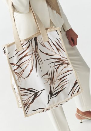 Borsa in tela con sfondo bianco e motivi di foglie marroni. Ha manici beige e una forma rettangolare strutturata.