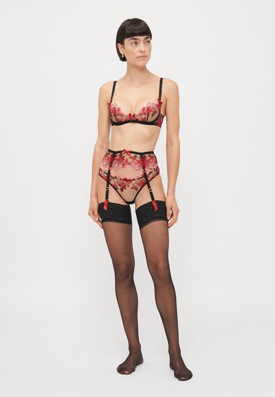 Ensemble de soutien-gorge en dentelle et porte-jarretelles noir avec broderie florale rouge, présentant des bretelles réglables et des accents en ruban. Bas noirs sur cuisse inclus.