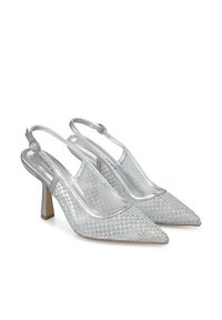 Tacchi slingback argento con punta affusolata, caratterizzati da un design in rete testurizzata e un tacco a blocco di 5 cm. Le cinghie sono regolabili con fibbie.