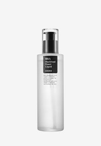 Bouteille en plastique transparent avec un couvercle à pompe noir. L'étiquette présente un texte noir sur fond blanc, indiquant le nom du produit et son objectif.