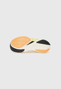 Running shoe outsole featuring a black rubber base, orange and cream accents, textured tread pattern, and notable flex grooves for traction.