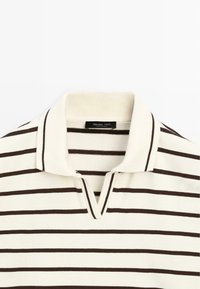 Gestreepte polo shirt in crème en donkerbruin, met een klassieke kraag, korte knopenrij en lichte stof. Label zichtbaar met merknaam.