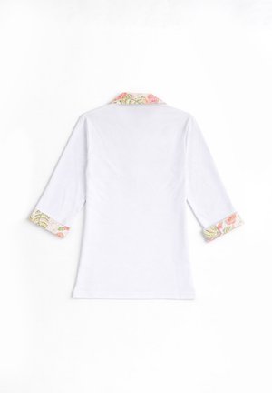 Chemise blanche à manches longues avec col et poignets à motifs floraux, posée à plat, vue de dos sur un fond blanc.