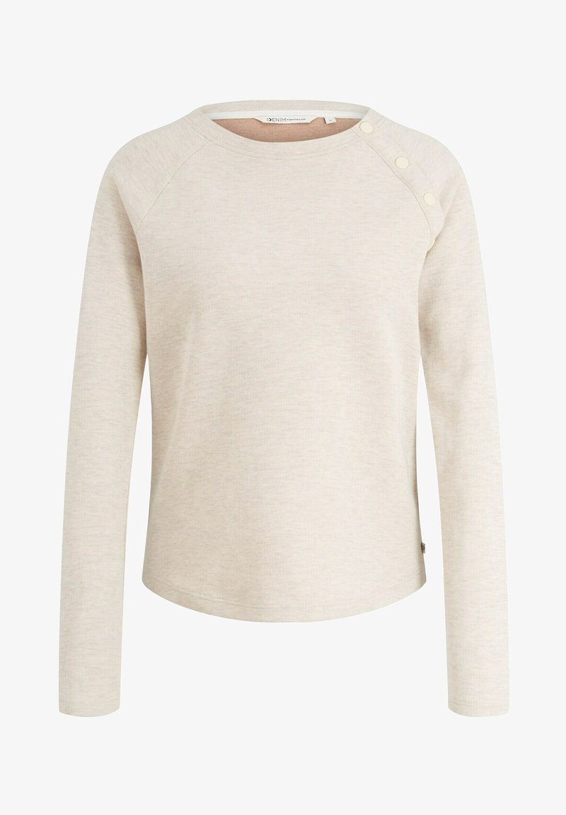 Vaalean beige pitkähihainen paita, joka on valmistettu pehmeästä kankaasta. Siinä on pyöreä kaula-aukko ja kolme koristepainiketta vasemmassa olkapäässä.