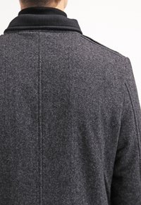 Cappotto grigio in lana con tessuto testurizzato, dotato di un colletto a coste nero e cuciture visibili lungo la schiena, progettato per una vestibilità su misura.