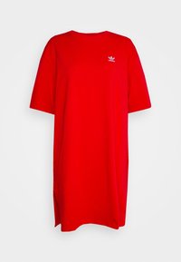Czerwona bawełniana sukienka t-shirtowa z krótkimi rękawami, okrągłym dekoltem i bocznymi rozcięciami. Ma małe białe logo Adidas na piersi.