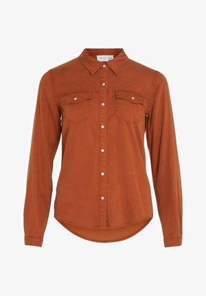 Ruosteenvärinen pitkähihainen nappipaita, jossa kaulus ja kaksi rintataskua, valkoisin painonapein ja hieman kaareutuvalla helmalla.