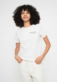 Bela bombažna majica s kratkimi rokavi in okroglim izrezom, na prsih temno modro natisnjen logotip "GANT1949".