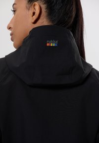 Veste noire imperméable avec un col montant et un petit logo coloré dans le dos. Texture lisse, design ajusté.