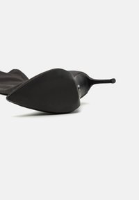 Sorte stiletto-hæler med spiss tå og gummiert, teksturert såle. Glatt overmateriale med et elegant og strømlinjeformet design.