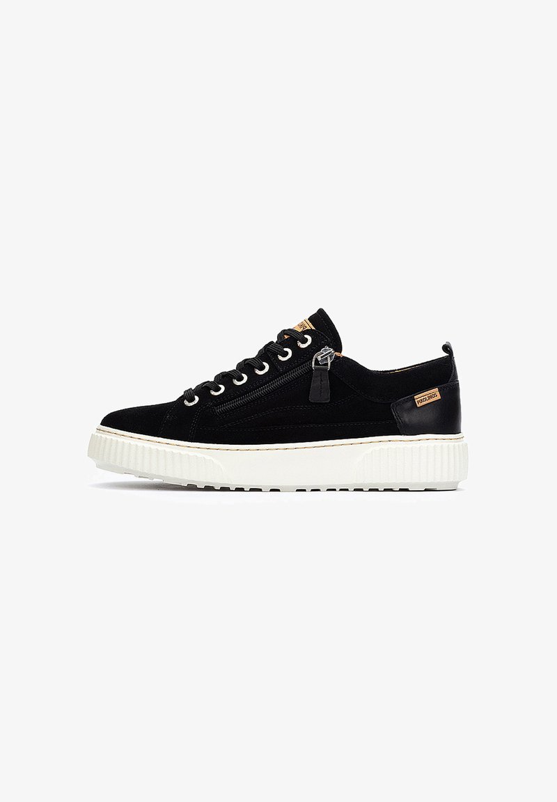 Zapatillas de ante negro con suela blanca texturizada, diseño de cordones, cremallera lateral y acentos de cuero. Presenta un parche con logo en la lengüeta.
