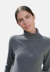 Pull en col roulé gris en tissu doux, avec un motif en losanges texturé à l'avant, un col côtelé et une coupe ajustée.