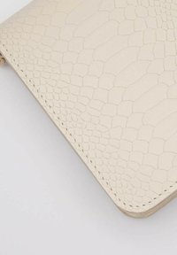 Portafoglio in pelle beige testurizzata con un motivo rettiliano, dotato di bordi arrotondati e cuciture visibili lungo la cucitura per un tocco di dettaglio in più.