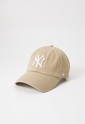 Beżowa czapka z daszkiem z białym haftowanym logo New York Yankees z przodu oraz oznaczeniem '47 po boku, prezentowana na jednolitym białym tle.
