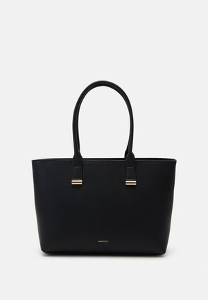 Sac cabas en cuir noir avec deux anses et des détails en métal doré, présentant une surface texturée et un petit logo près de la base.