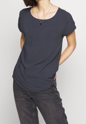 Granatowy t-shirt z krótkim rękawem wykonany z miękkiego materiału, z okrągłym dekoltem i luźnym krojem, zestawiony z ciemnymi dżinsami.