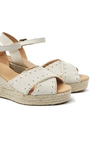 White leather espadrille wedges with cross-strap design, jute-wrapped sole, and stitched detailing along the upper.